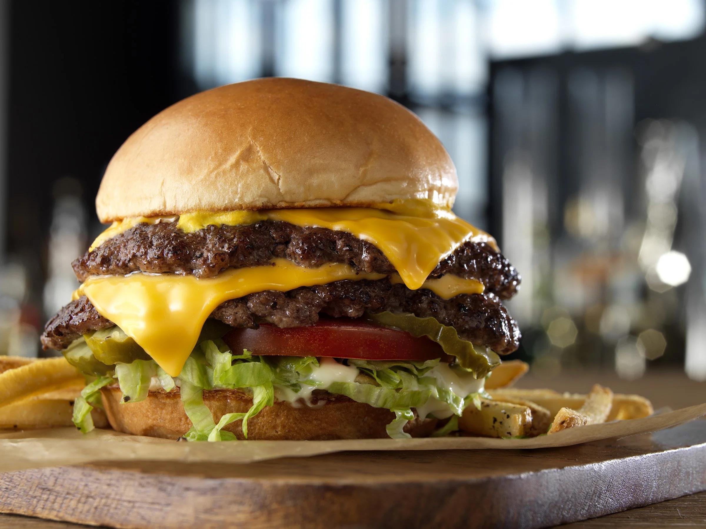 Representative photo: a double cheeseburger with melted American cheese, lettuce, tomato and pickle